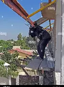 Worker working high up on a loose makeshift wooden ledge under a steel beam